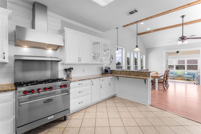 kitchen featuring white cabinetry, wall chimney range hood, designer range, and dark stone counters