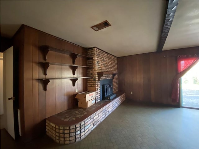 unfurnished living room featuring beamed ceiling and wood walls