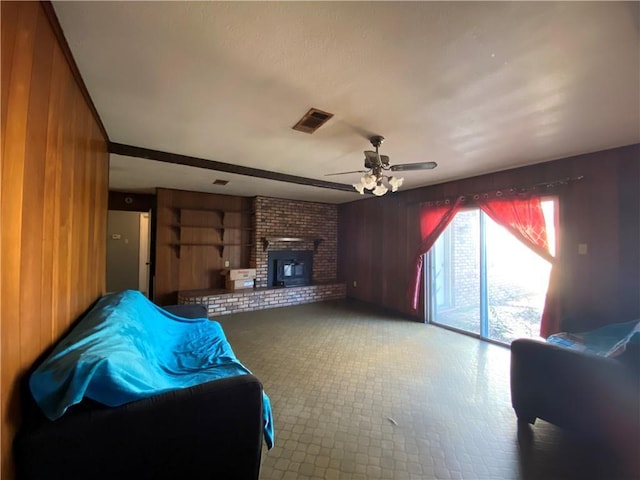 living room featuring a brick fireplace, ceiling fan, and wood walls