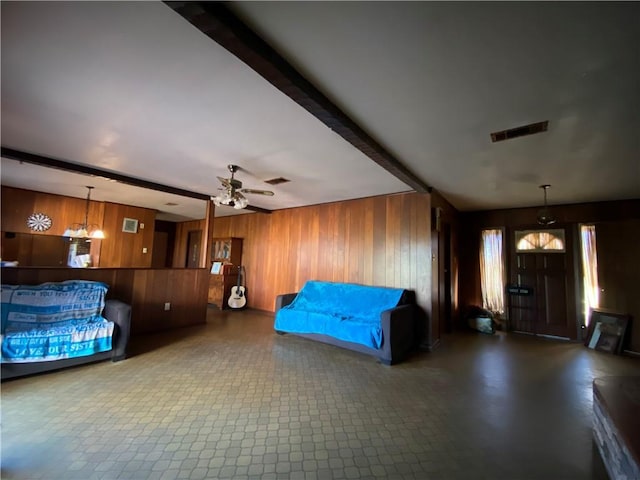 bedroom with ceiling fan, wooden walls, and beam ceiling