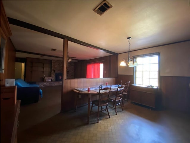 dining room featuring ceiling fan with notable chandelier and a brick fireplace