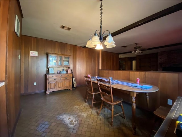 dining room with beam ceiling and wood walls