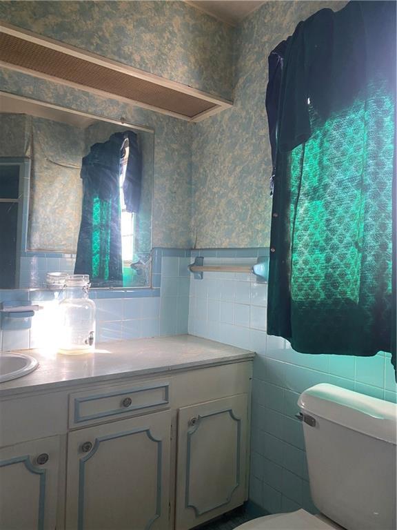 bathroom featuring vanity, toilet, tile walls, and plenty of natural light