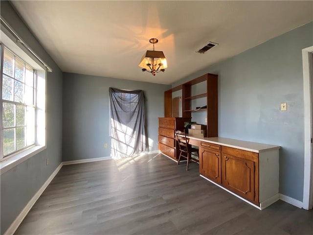 unfurnished office featuring a healthy amount of sunlight, dark hardwood / wood-style floors, and a notable chandelier