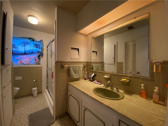 bathroom with toilet, tile walls, vanity, and walk in shower