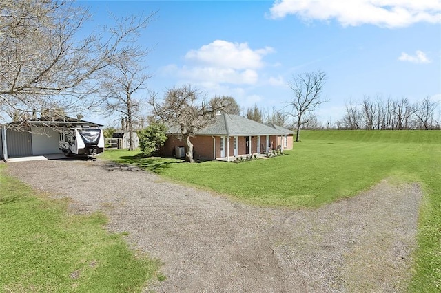 exterior space featuring an outbuilding, a lawn, brick siding, and driveway