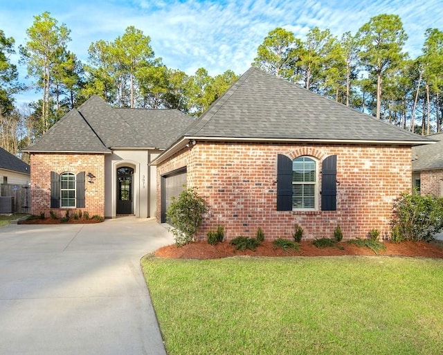 french country home featuring a garage, a front yard, and central AC unit