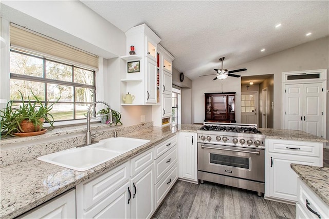 kitchen featuring kitchen peninsula, sink, white cabinets, stainless steel range, and lofted ceiling