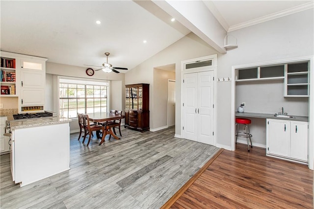 kitchen featuring hardwood / wood-style floors, white cabinets, sink, ceiling fan, and lofted ceiling