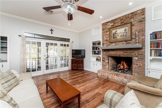 living room with french doors, crown molding, a fireplace, and hardwood / wood-style floors