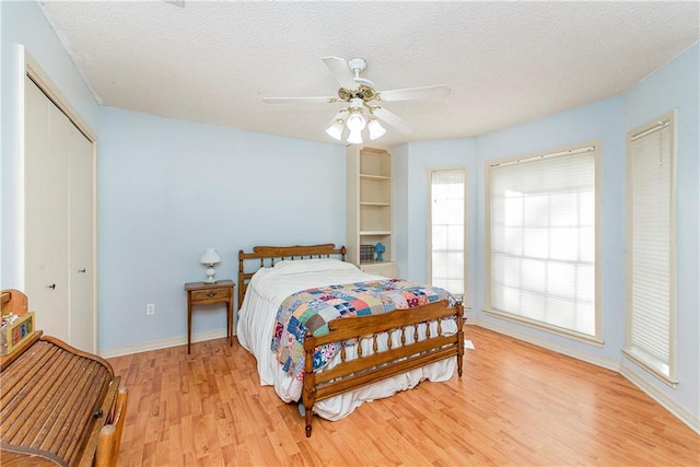 bedroom with ceiling fan, a textured ceiling, light hardwood / wood-style flooring, and a closet