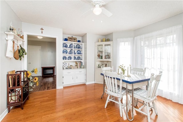 dining room with ceiling fan, hardwood / wood-style floors, and a textured ceiling