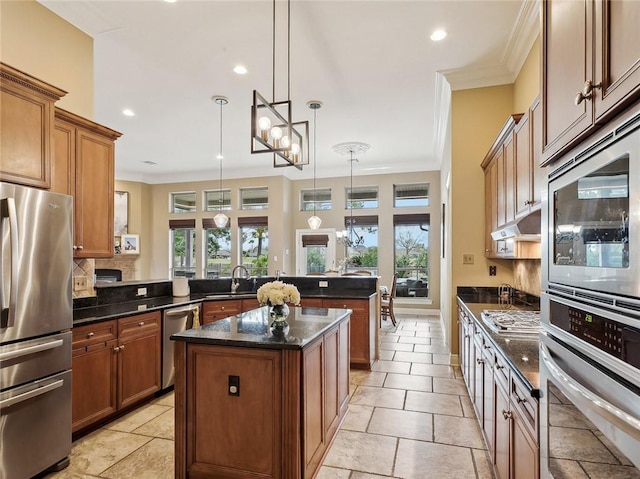 kitchen featuring crown molding, kitchen peninsula, hanging light fixtures, appliances with stainless steel finishes, and a kitchen island