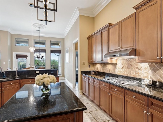 kitchen with decorative light fixtures, a center island, stainless steel gas cooktop, and dark stone countertops