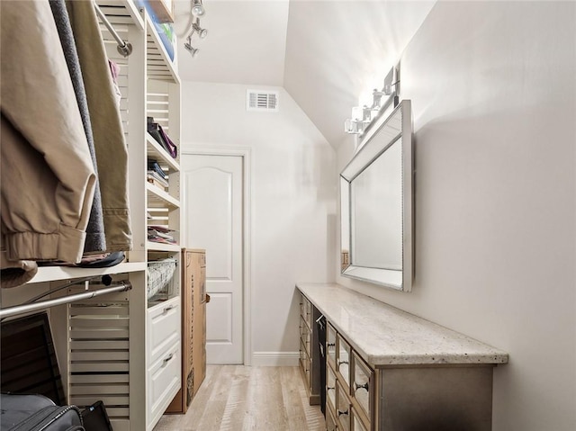 walk in closet with vaulted ceiling and light hardwood / wood-style floors