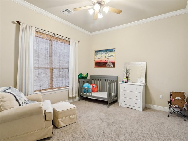 bedroom with ceiling fan, light colored carpet, a nursery area, and crown molding