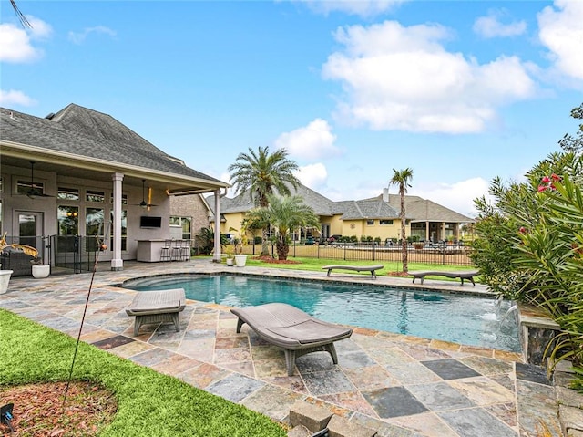 view of swimming pool featuring ceiling fan, a patio area, exterior bar, and pool water feature