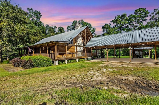 view of front of house featuring a chimney, a front lawn, and metal roof