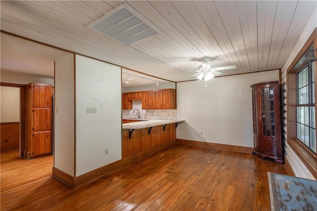 kitchen with visible vents, a sink, wood-type flooring, brown cabinetry, and decorative backsplash