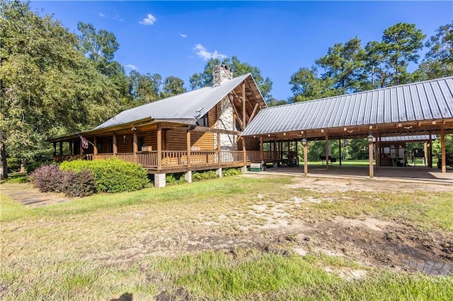 view of side of property with a carport, metal roof, and a chimney