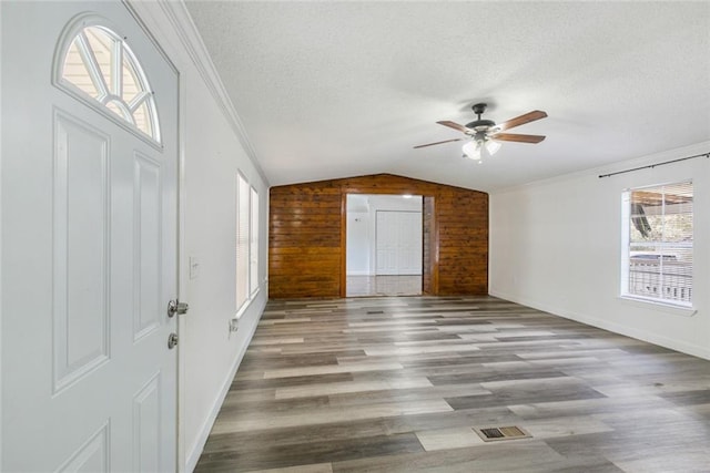 entryway featuring lofted ceiling, wooden walls, a textured ceiling, and light hardwood / wood-style flooring