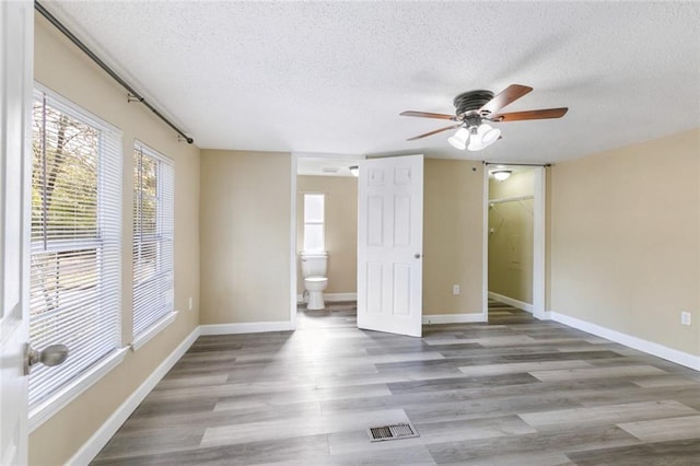 empty room featuring ceiling fan, hardwood / wood-style floors, and a textured ceiling