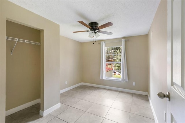 unfurnished bedroom featuring a textured ceiling, a closet, ceiling fan, and light tile patterned flooring