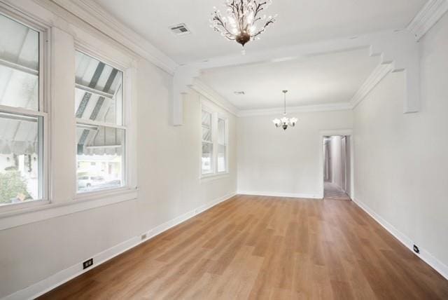 empty room featuring crown molding, an inviting chandelier, and hardwood / wood-style flooring