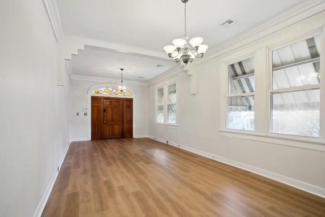 interior space with hardwood / wood-style flooring, plenty of natural light, crown molding, and a notable chandelier