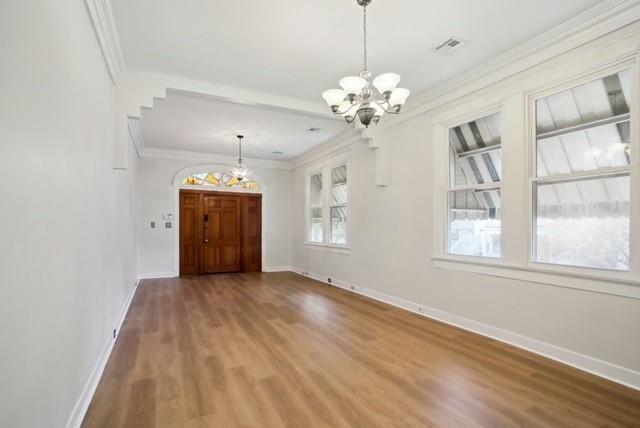 4937-39 S Miro St, New Orleans, LA 70125 - unfurnished dining area featuring wood finished floors, baseboards, ornamental molding, and an inviting chandelier