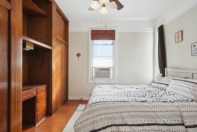 bedroom with light hardwood / wood-style floors, cooling unit, and ceiling fan