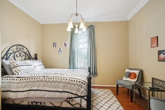 bedroom featuring hardwood / wood-style flooring, a chandelier, and crown molding