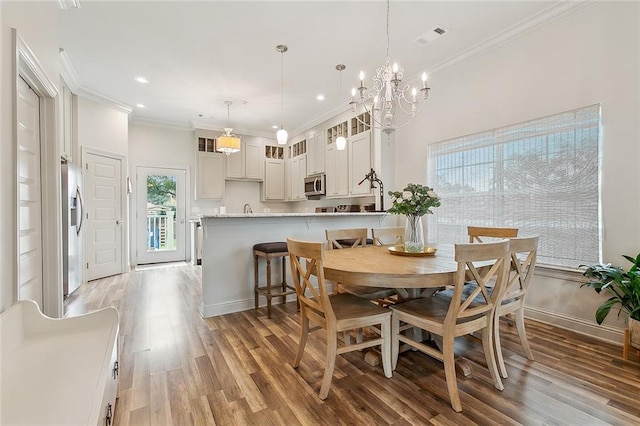 dining area featuring crown molding, plenty of natural light, sink, and light hardwood / wood-style floors