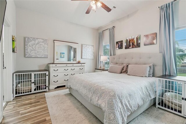 bedroom with multiple windows, light hardwood / wood-style flooring, and ceiling fan