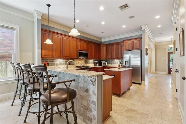 kitchen featuring appliances with stainless steel finishes, decorative light fixtures, kitchen peninsula, and a kitchen bar