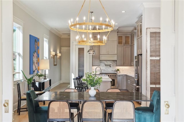 dining area with ornamental molding, sink, and a notable chandelier