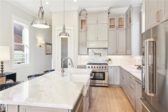 kitchen featuring high end appliances, decorative light fixtures, a center island with sink, light stone countertops, and decorative backsplash