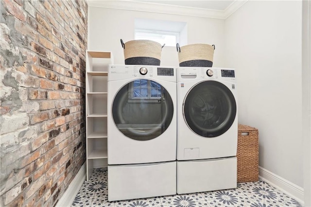 laundry area featuring light tile patterned flooring, washing machine and clothes dryer, brick wall, and ornamental molding