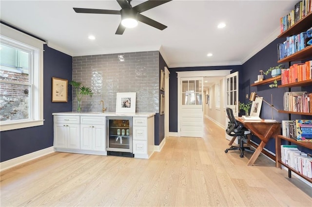 bar featuring white cabinetry, sink, beverage cooler, ornamental molding, and light hardwood / wood-style floors