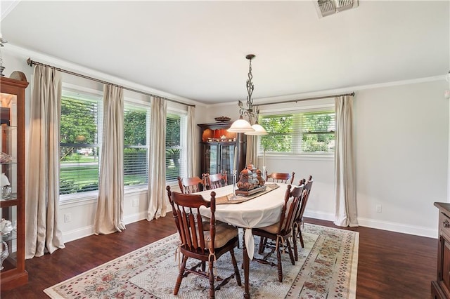 dining room with dark wood-type flooring, crown molding, and a healthy amount of sunlight