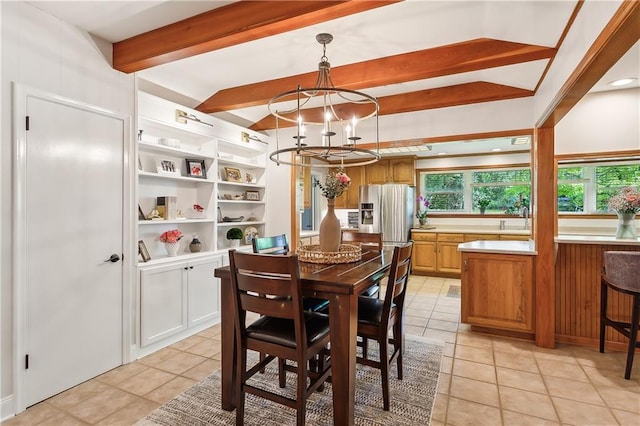 dining room featuring sink, light tile patterned floors, beamed ceiling, and an inviting chandelier