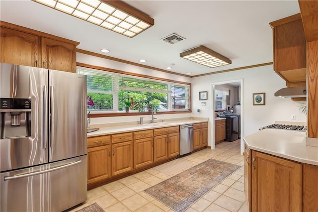 kitchen with sink, light tile patterned floors, appliances with stainless steel finishes, and crown molding