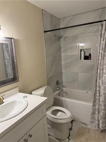 full bathroom featuring shower / bath combo, vanity, and toilet