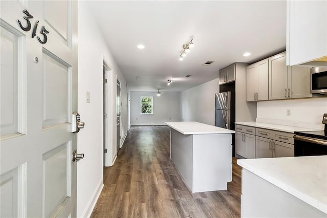 kitchen featuring a kitchen island, dark hardwood / wood-style flooring, stainless steel appliances, gray cabinets, and ceiling fan