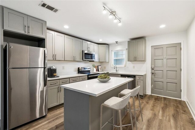 kitchen featuring appliances with stainless steel finishes, sink, a kitchen island, dark hardwood / wood-style flooring, and gray cabinets