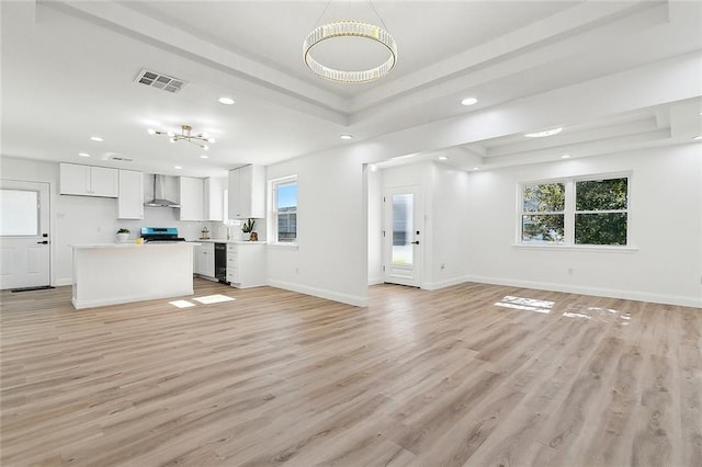 unfurnished living room featuring light hardwood / wood-style flooring, a raised ceiling, and wine cooler