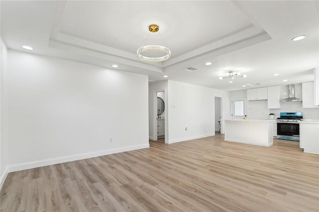 unfurnished living room with a raised ceiling and light hardwood / wood-style flooring