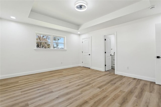 empty room featuring light hardwood / wood-style floors and a raised ceiling