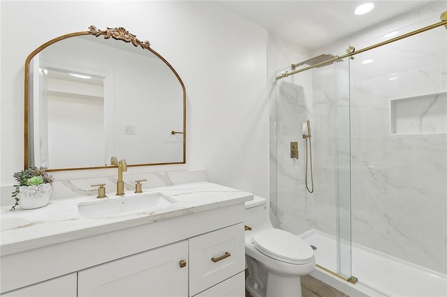 bathroom with vanity, a shower with shower door, and toilet