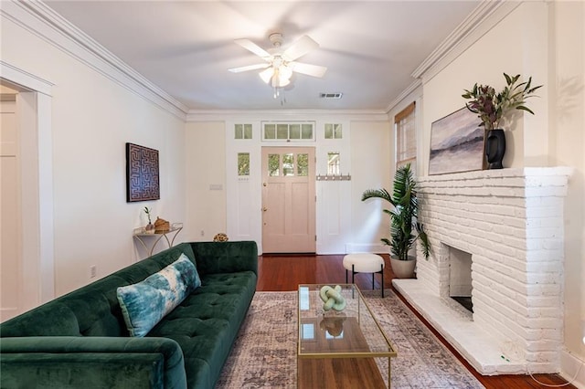 living room featuring ceiling fan, dark hardwood / wood-style flooring, crown molding, and a fireplace